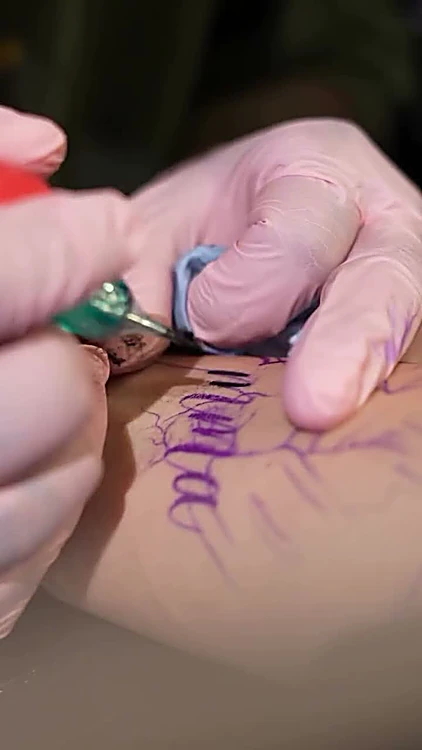 La máquina repasa con tinta negra las letras calcadas en violeta, con guantes rosas.