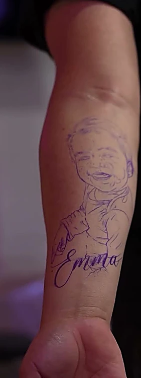 Antebrazo con la calca violeta de un retrato y un nombre en letra manuscrita.