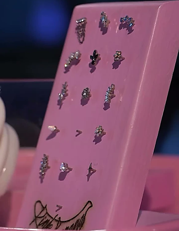 Exhibidor rosa con joyería para piercing en plata.