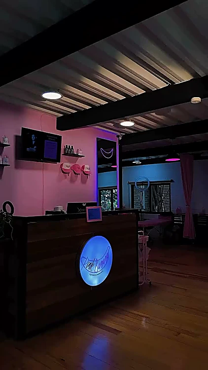 Recepción de madera con luz rosa y un logo iluminado en azul.